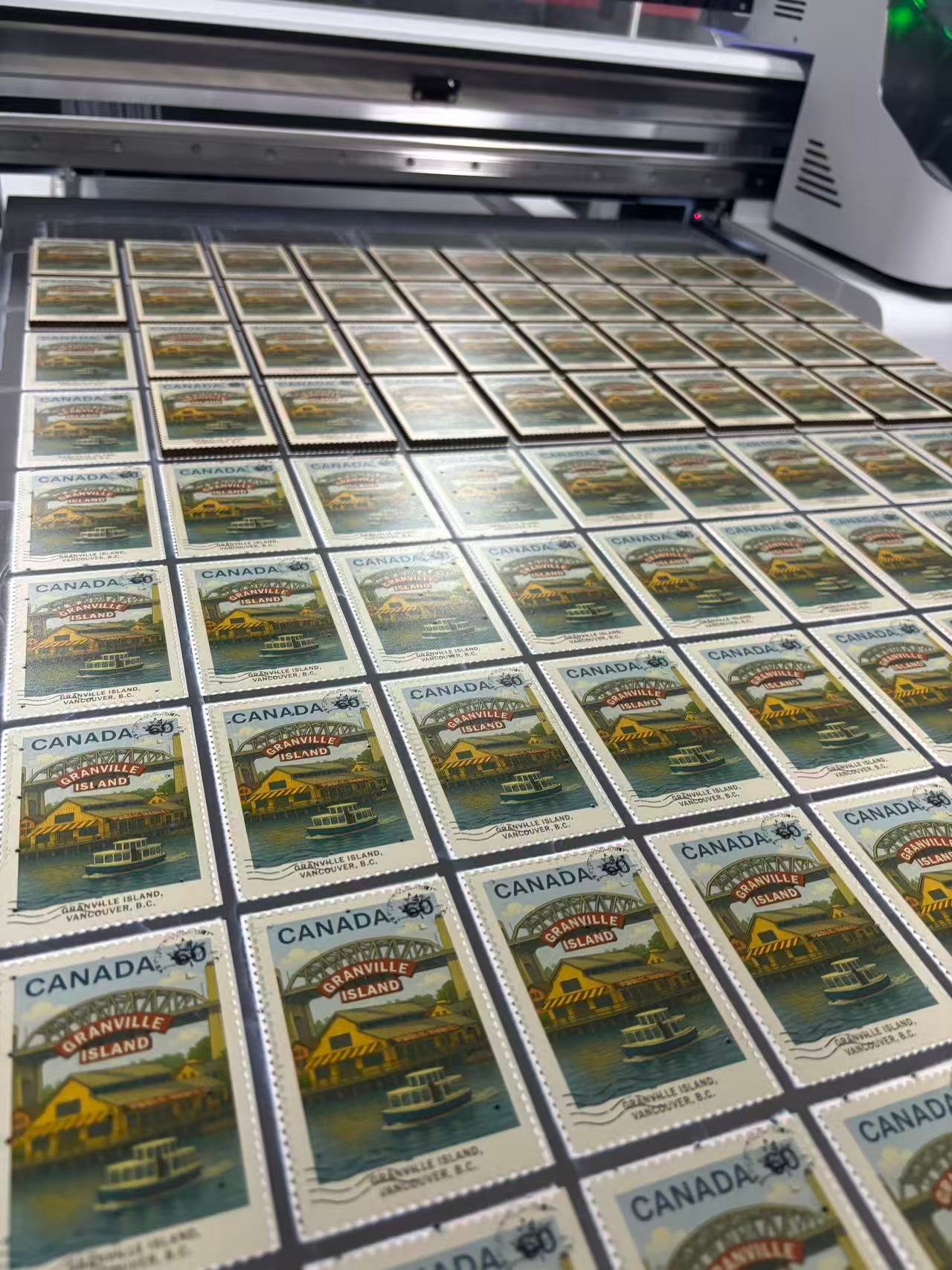 Custom stamp-style MDF souvenir magnets on UV printing machine full production bed