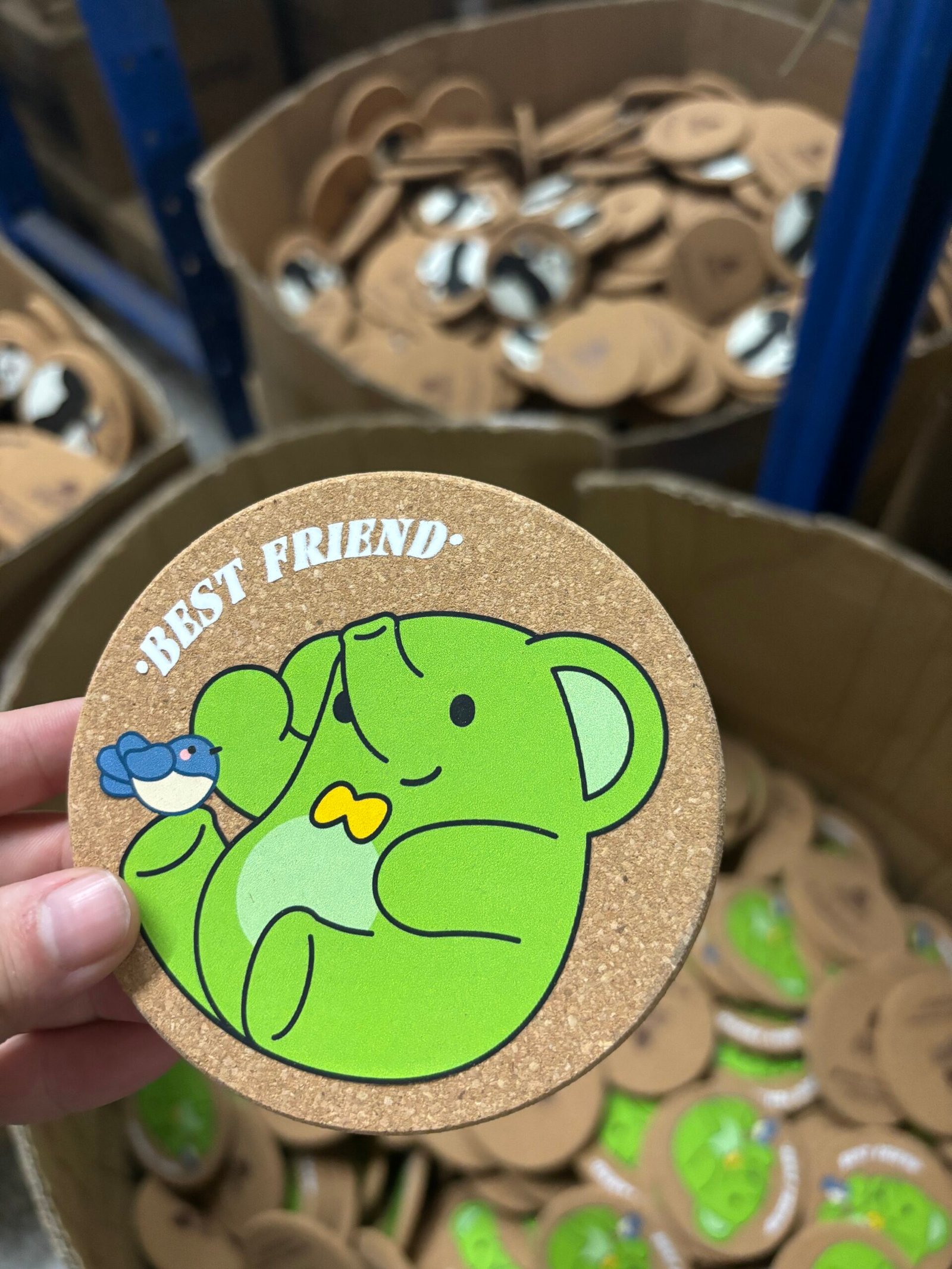 Hand holding finished custom cork coaster in warehouse