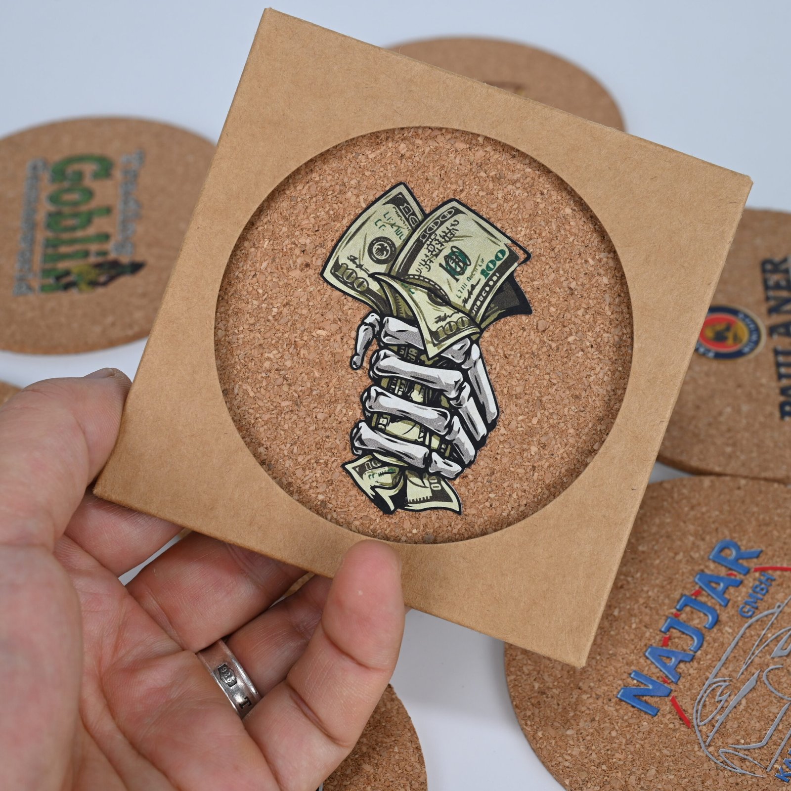 Hand holding square cork coaster with detailed custom print showing full-color quality