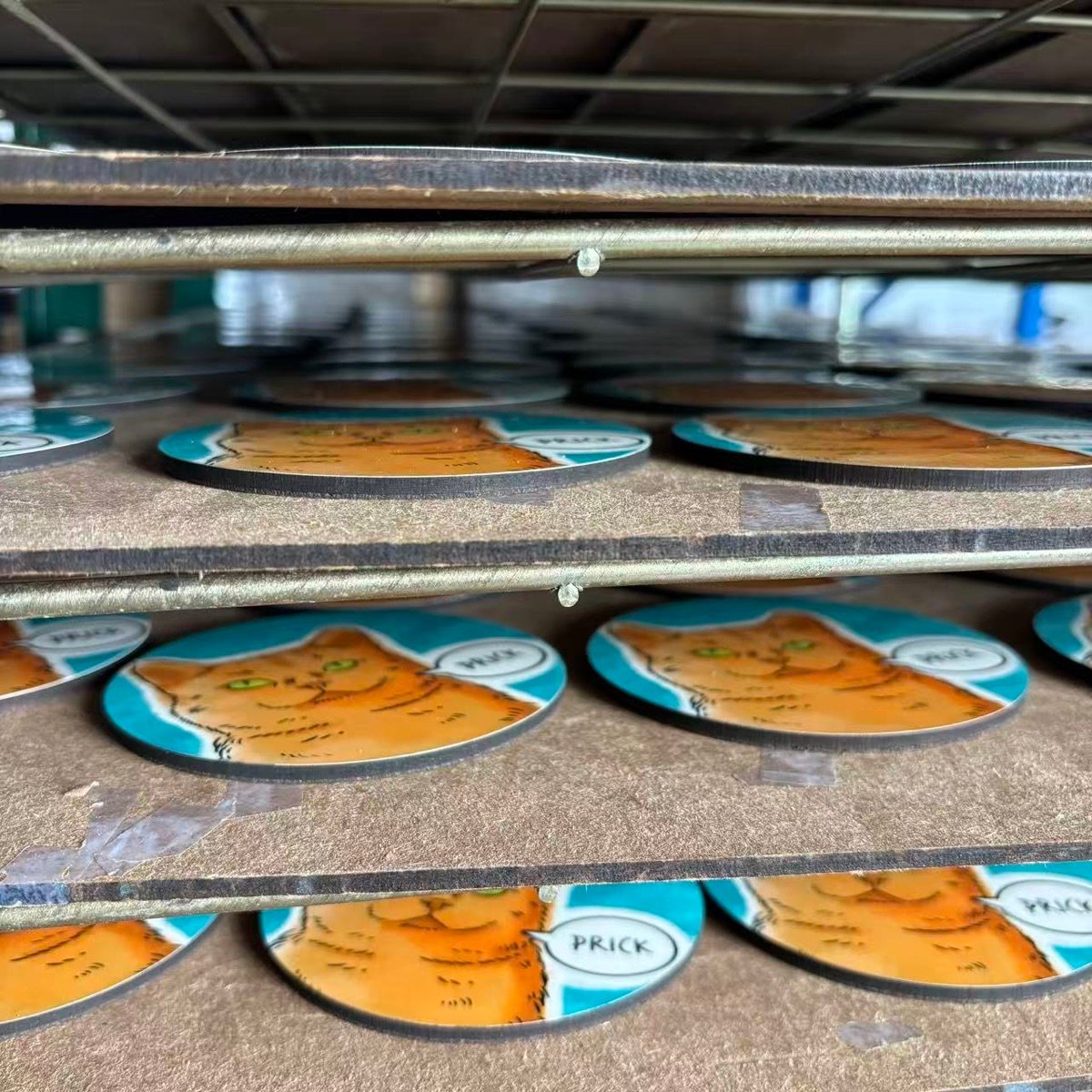 Printed souvenir coasters cooling on drying racks after sublimation press